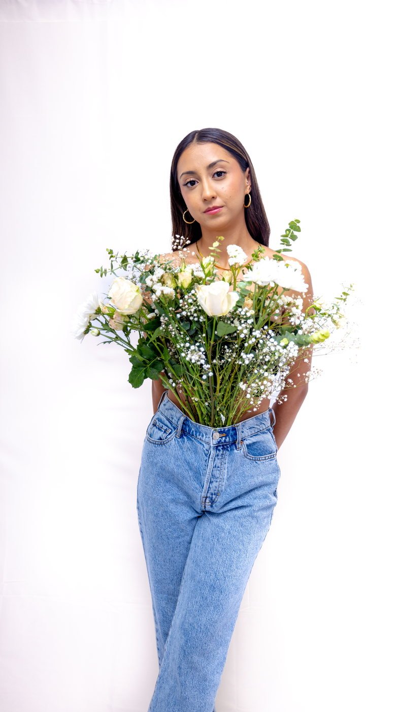 Senior holding a bouquet against a white wall