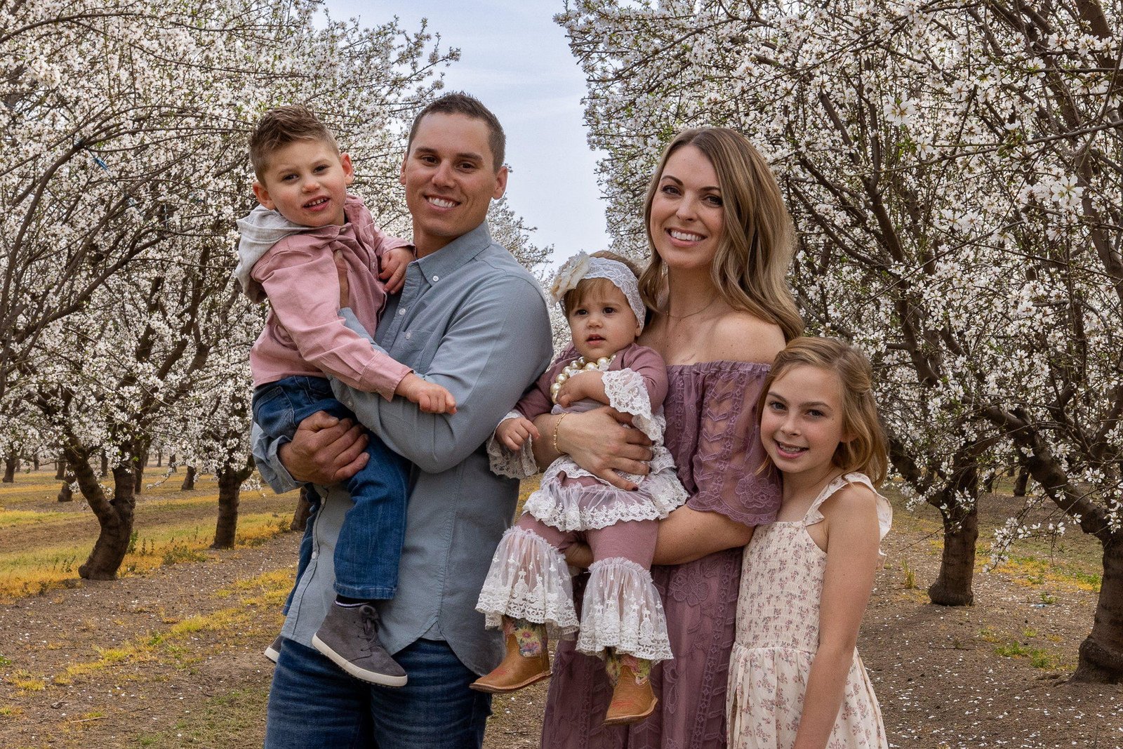 Family of five photographed in a blossoming orchard