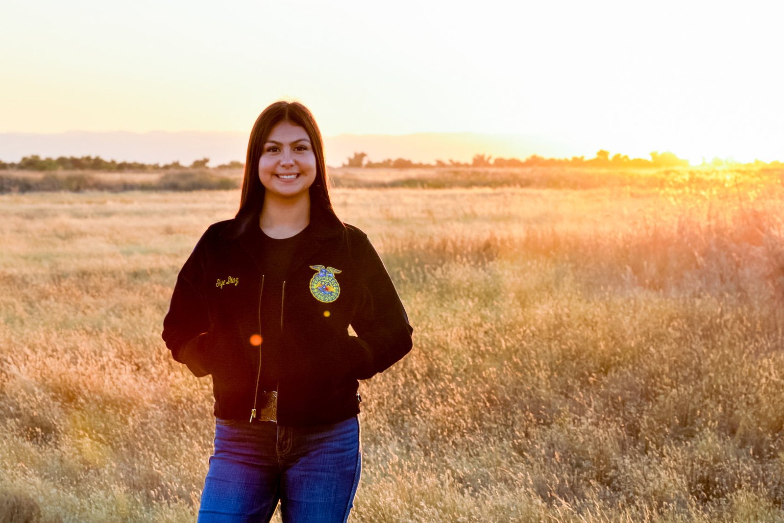 Senior in an FFA jacket photographed at golden hour