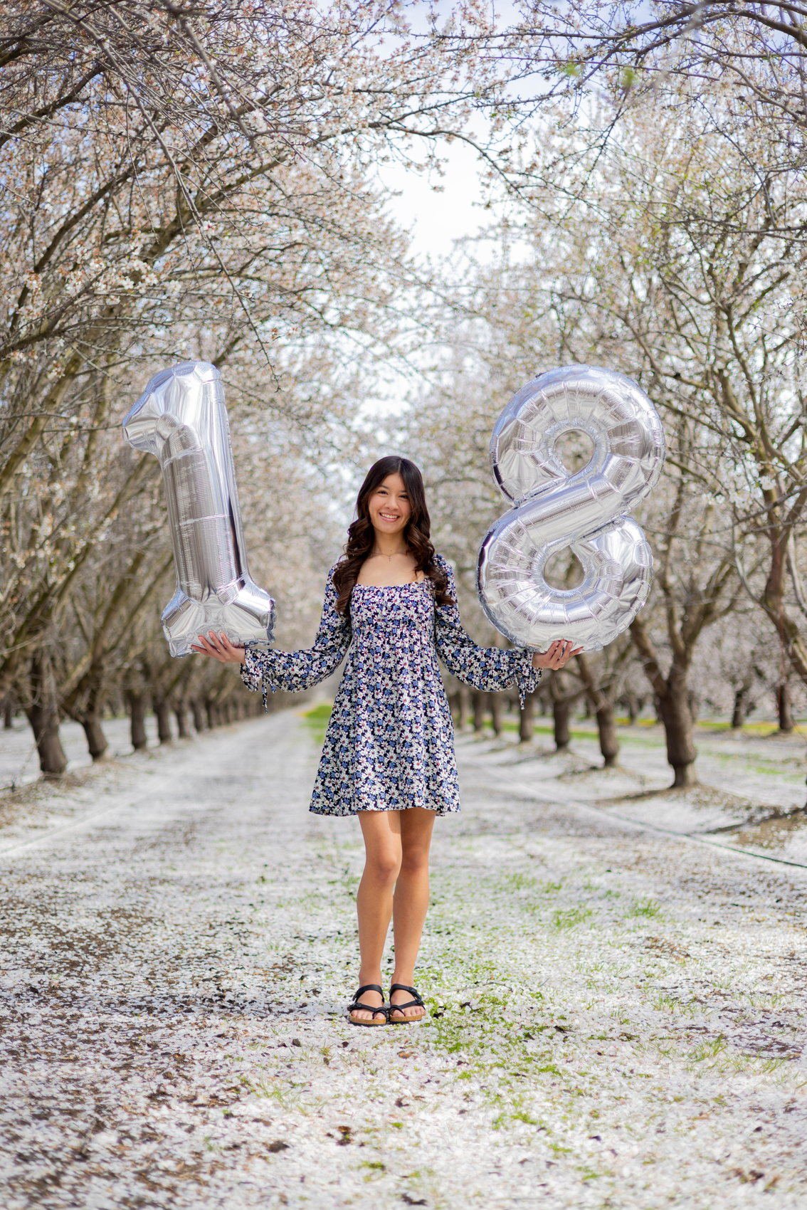 Senior portrait with eighteen balloons in the orchard
